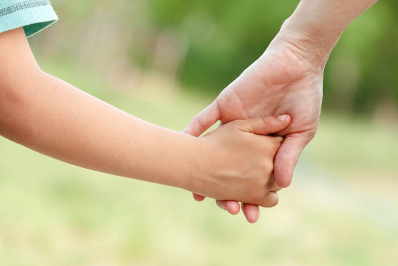 Foster parent holds a child's hand.